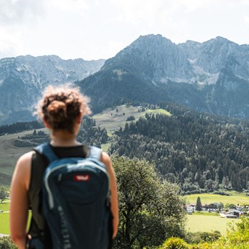 Eine Wanderin mit Rucksack blickt auf die atemberaubenden Berge in der Ferne.